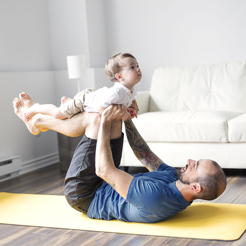 Vater und Sohn genießen gemeinsames Turnen auf der Matte: richtiges Trainingsprogramm verbessert die Flexibilität der Muskeln und kann Muskelverletzungen verringern.