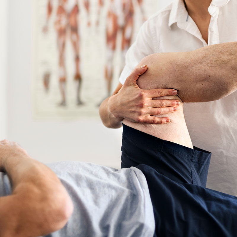 Orthopäde untersucht das Bein eines Mannes auf Anzeichen von Muskelverletzung oder Zerrung zur Diagnosestellung.