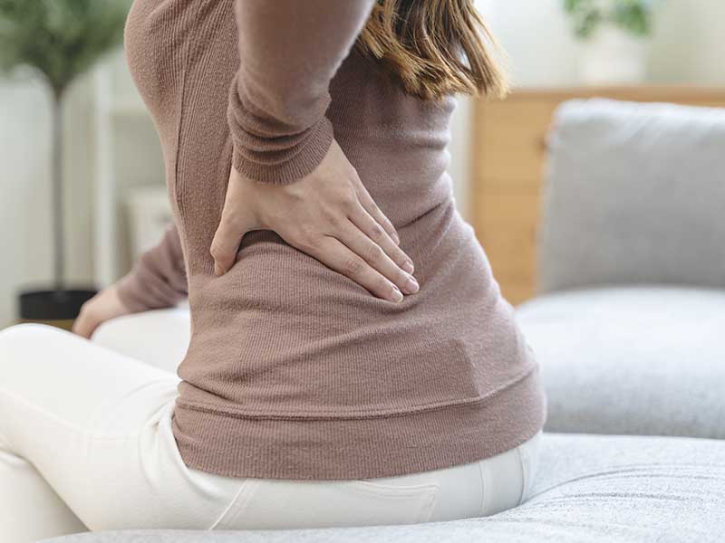Schmerzen im Sitzen – typisches Symptom bei Hexenschuss Frau mit Hexenschuss hat Schmerzen beim Sitzen