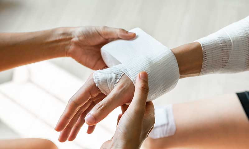 Versorgung einer verletzten Hand mit Verband als Teil der Standardbehandlung von Wunden
